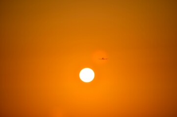  The plane is gaining altitude, with evenly spread wings. Flies in orange sunset in the spot of reflection.