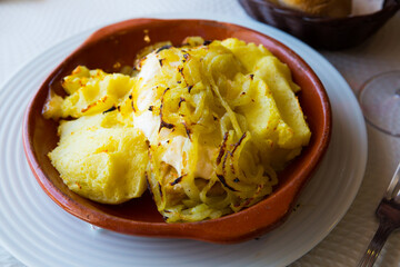 Delicate cod fish baked with mashed potatoes and onion served in pottery..
