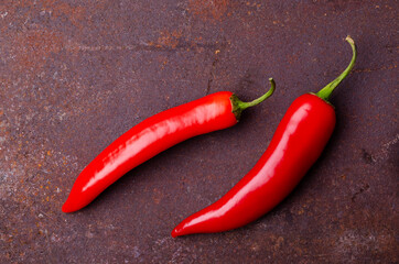 Red pepper pod on a rusty brown metal background.