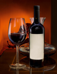 Bottle of red wine with decanter on a table and a fireplace behind