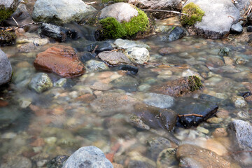 Slow shot of the stream flowing in the mountains outdoors in summer