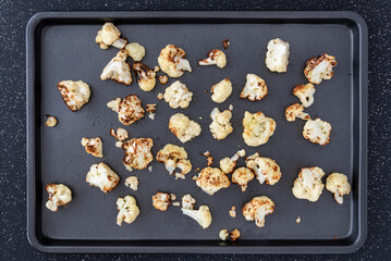 Fototapeta na wymiar Metal baking sheet with roasted chopped up cauliflower 