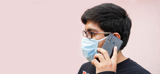 man with mask and black sweater talking on the phone