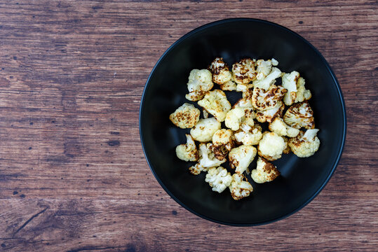 Fresh Roasted Cauliflower In A Ceramic Black Dinner Bowl On A Rustic Wood Table
