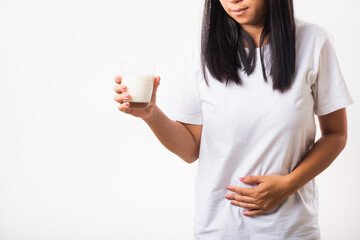 Closeup young woman intolerant use hand holding glass milk she is bad stomach ache she has bad lactose intolerance unhealthy problem with dairy food products, studio shot isolated on white background