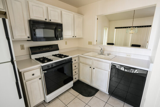Clean 1990s style suburban condo kitchen with light colored cabinets and tile floor.