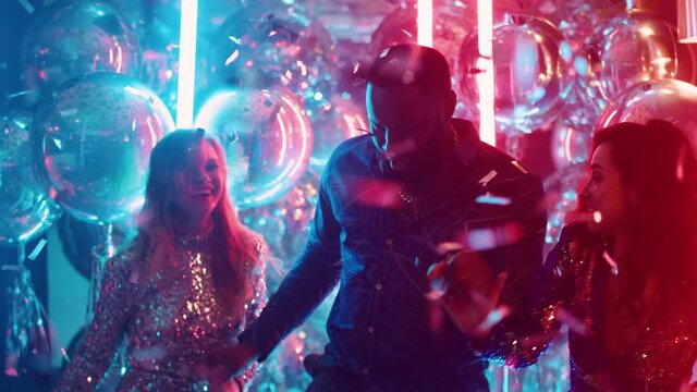 African guy and european girls dancing in nightclub. Friends having fun at party