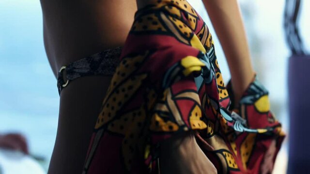 Woman takes off red with blue & yellow flower print kaftan to reveal brown snake print bikini. Slow motion
the woman takes off her pareo and stays in a bikini.