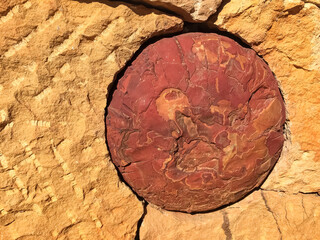 Close up of a wall with an implemented round red stone in sunshine, Barichara, Colombia