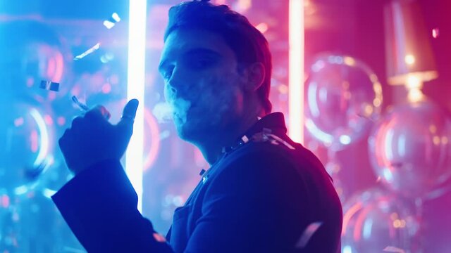 Attractive guy looking camera at party. Man dancing under confetti in club