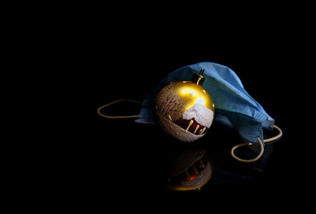 Fototapeta premium Christmas ball and mask from covid19 lie on black surface