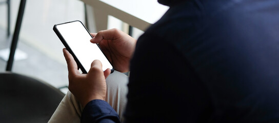 Mock up smartphone of hand holding black mobile phone with blank white screen.