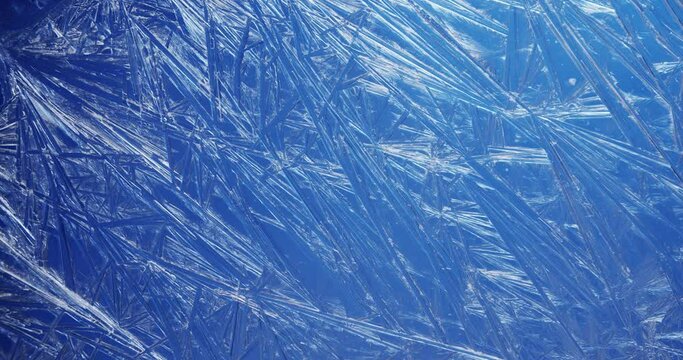 Frost covered window with lights shimmering and glittering over ice crystals.