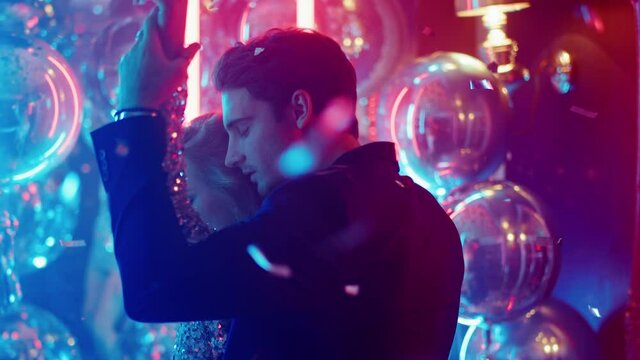 Hot girl and guy moving bodies at party. Couple standing close in nightclub