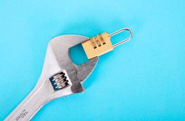 A combination lock held by a pair of live pliers on a blue background