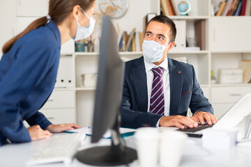 Portrait of businessman wearing protective face mask working in office with female colleague. Pandemic precautionary concept