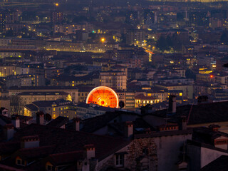 Obraz premium Bergamo, Italy. The Ferris wheel illuminated in red in the evening. Christmas time. Fun attraction. Aerial view from the old town at the top of the hill
