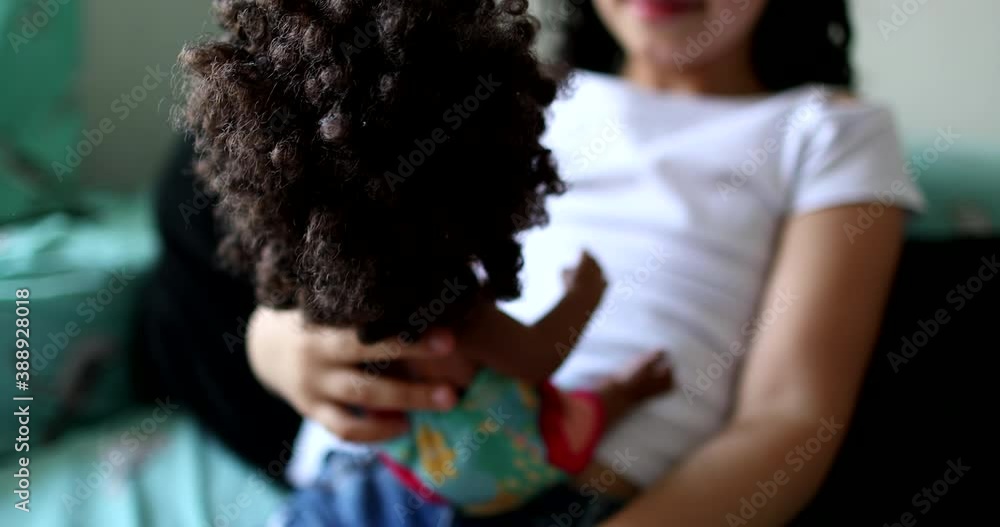 Wall mural Hispanic little girl child playing with black doll