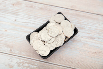 Small saucer full of dollar coins on the table