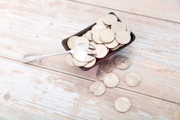 A small dish full of dollar coins and a spoon on the table
