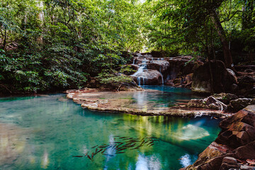 Beautiful blue waterfall with fish swimming in Tropical  forest at Erawan waterfall National Park Kanchanaburi, Thailand.