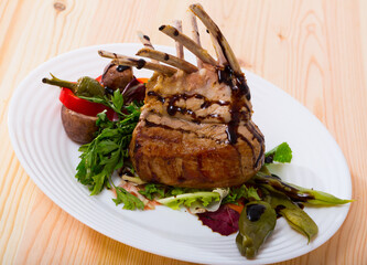 Young lamb ribs served with vegetables and herbs on plate