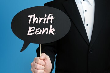 Thrift Bank. Businessman holds speech bubble in his hand. Handwritten Word/Text on sign.