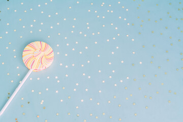 Round multicolored Lollipop, blue background with gold bright confetti. Flat styling style. Holiday concept