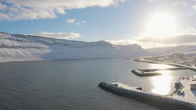 Iceland westfjord aerial view above snowy white harbor town on sunny winter day