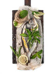 dietary steamed stuffed sea bream or dorado fish with lemon and fresh herbs, top view on a wooden cutting board on a white background, isolated