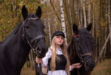 Obraz premium A young slender girl with blonde hair leads two horses .