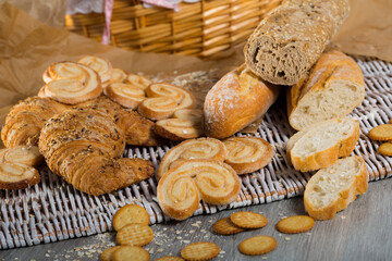 Fototapeta na wymiar Assortment of fresh baked goods on wicker mat with basket on wooden background