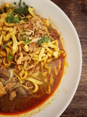 Khao Soi Kai, Thai spicy food in white blow on wooden table, Thai spicy soup. Thai Food. Northern Thai Style Curried Noodle Soup with Chicken