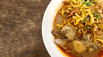 Khao Soi Kai, Thai spicy food in white blow on wooden table, Thai spicy soup. Thai Food. Northern Thai Style Curried Noodle Soup with Chicken