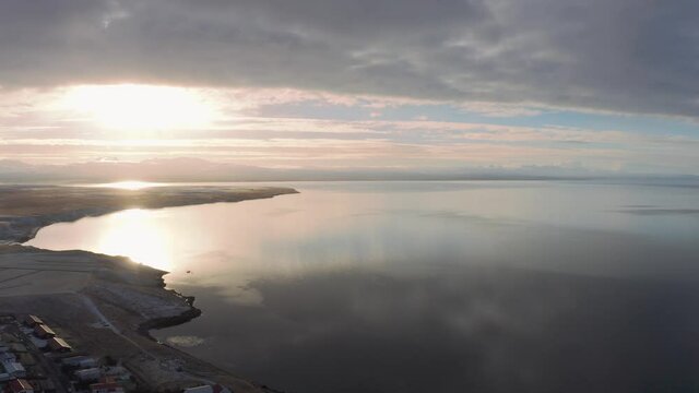 Flying above Iceland westfjord landscape town at sunset, scenic aerial view of artic ocean, surreal cloudscape reflection