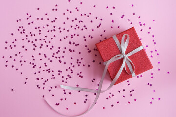 Gift box, pink stars sparkles on pink pastel background. Christmas, New Year, Birthday, Valentine's day greetings concept. Copy space, flat lay, top view.