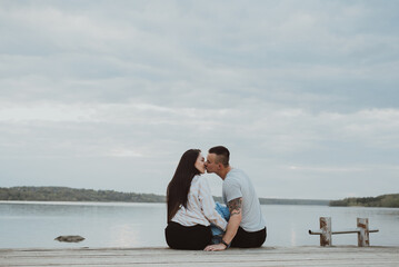 Young happy family sitting on the pier in the summer