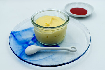 Vanilla pudding in a glass jar with red berries sauce isolated on white background
