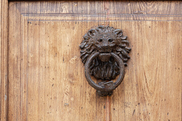 detail of a traditional old metal lion-shaped doorknob on the old wooden door