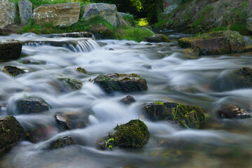 Fototapeta na wymiar Rough river, water flows among stones. Long exposure,.