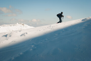 Man skitouring in the mountains. Healthy activity on snow. Good weather for winter sport and recreation. 