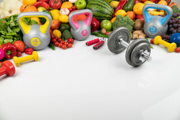 Fitness concept. Healthy nutrition: fruits and vegetables. Equipment for fitness exercises: weighing machine and dumbells. White background.