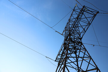 High voltage tower against beautiful blue sky, low angle view