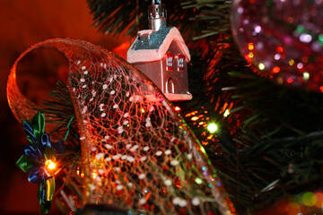 Christmas tree decoration "House" close-up, hanging on the tree. Christmas tree decoration in the form of a house and a festive ribbon on the background of a Christmas tree.