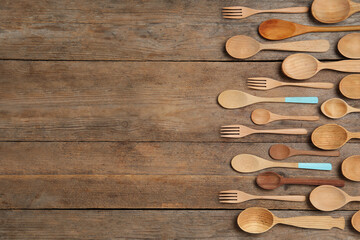 Many different spoons and forks on wooden table, flat lay with space for text. Cooking utensils