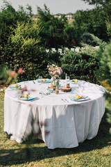 Gorgeous wedding table setting in a greenery outdoor venue for a celebration. Open air reception with dinner and garden party. Modern rustic style decor inspiration. Marriage, or anniversary planning.