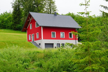 Fototapeta na wymiar Schönes rot Bungalowhaus mit grüner Wiese , Das Haus liegt in einer schönen und ruhigen Gegend