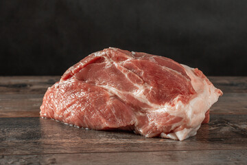 RAW meat on dark wooden background. Raw meat piece of pork on rustic wooden table is ready for cooking.
