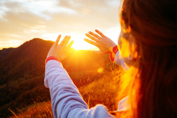 Carefree hipster girl enjoying nature on top of mountain with sunset.