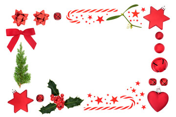 Abstract Christmas border with red bauble decorations, stars, fir, holly & mistletoe on white background. Festive composition for greeting card, gift tag or invitation. Top view, flat lay, copy space.